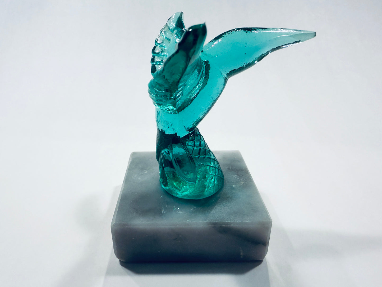 A translucent turquoise glass mermaid figurine with a raised wing Made In Italy 
