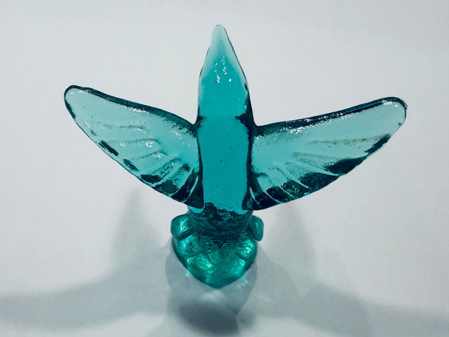 A small translucent aqua blue bird figurine with wings spread, standing on a matching base Made In Italy 