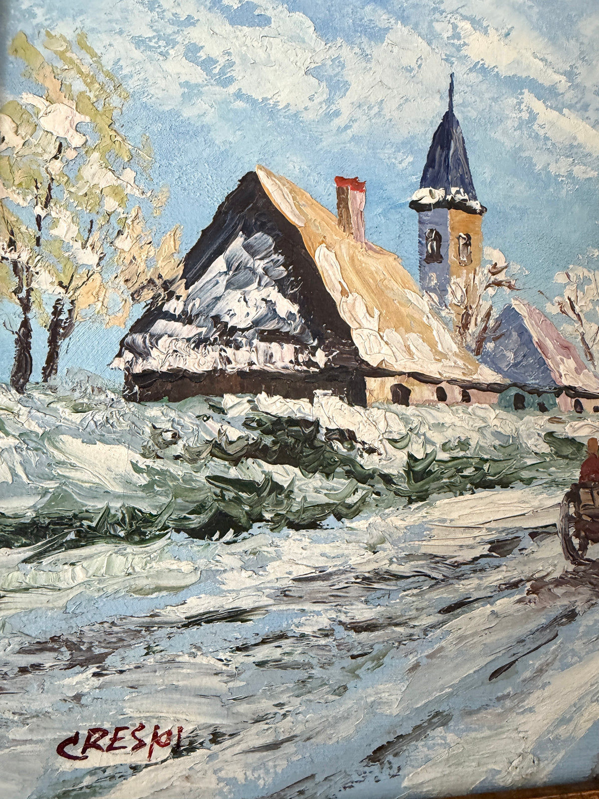 A painted winter village scene with snow-covered rooftops, a church steeple, trees, and a snowy road. The artwork fills the frame, with a visible artist signature in the lower left.