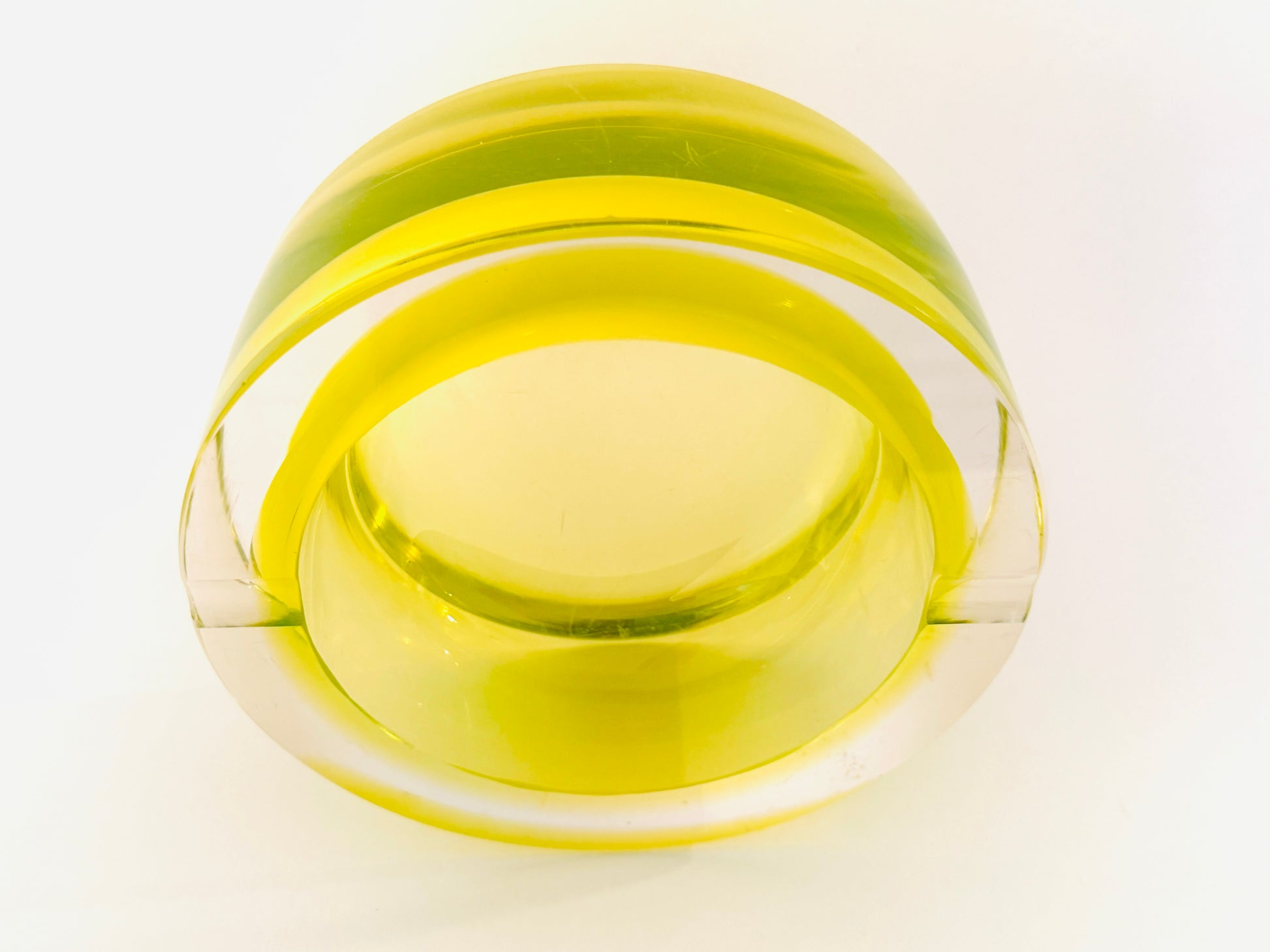 A translucent yellow green glass bowl ashtray with a thick, rounded rim, photographed from a top
