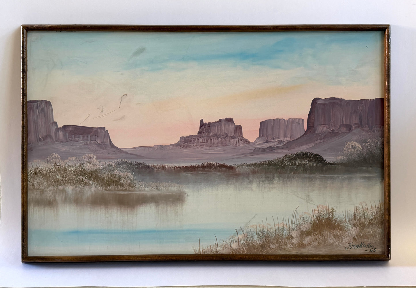Juan Nakai signed landscape painting depicting a serene river or lake with misty banks, distant butte formations, and a pale sky