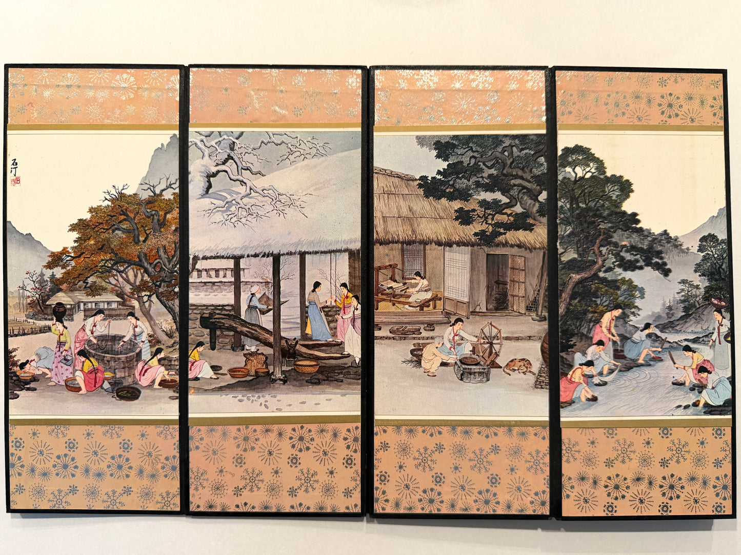 Traditional Japanese folding screen with scenes of people in a village setting.