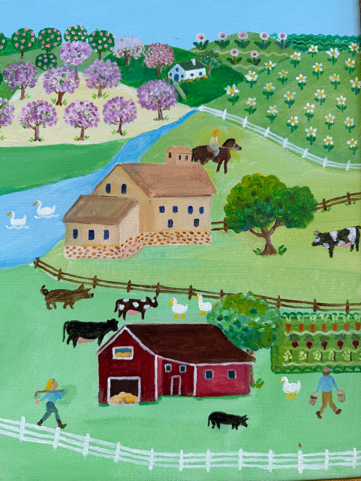 A framed folk art landscape painting depicting a rural scene with houses, barns, trees, fields, and a river Signed Kay Benham 06