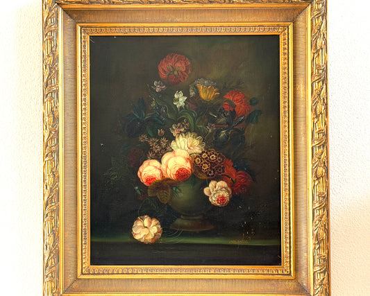 A framed still life oil painting depicting a vibrant bouquet of red, pink, and white flowers in a dark vase against a dark background, housed in an ornate gold frame.