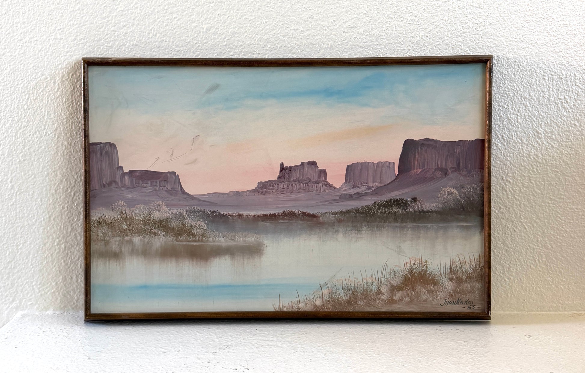 Juan Nakai signed landscape painting depicting a serene river or lake with misty banks, distant butte formations, and a pale sky