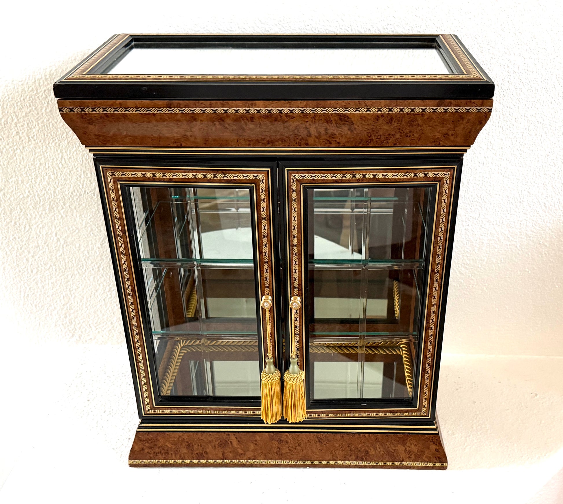 A vintage-style wooden display cabinet with two glass doors, gold tassel handles, and ornate gold and black inlay detailing, Made in Italy 