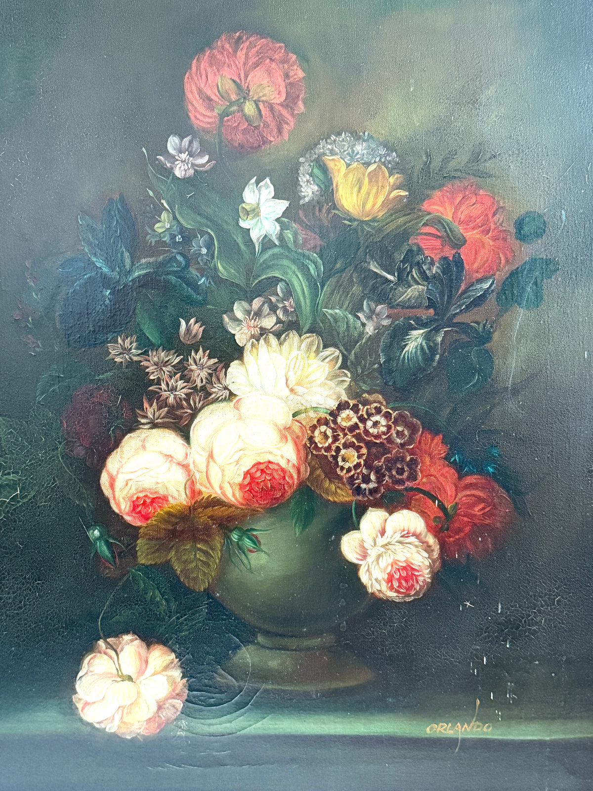 A classical still life oil painting depicting a vibrant bouquet of flowers in a green vase against a dark, moody background. The bouquet features prominent red, yellow, white, and pink blossoms with green leaves, with one flower falling from the vase at the bottom left.