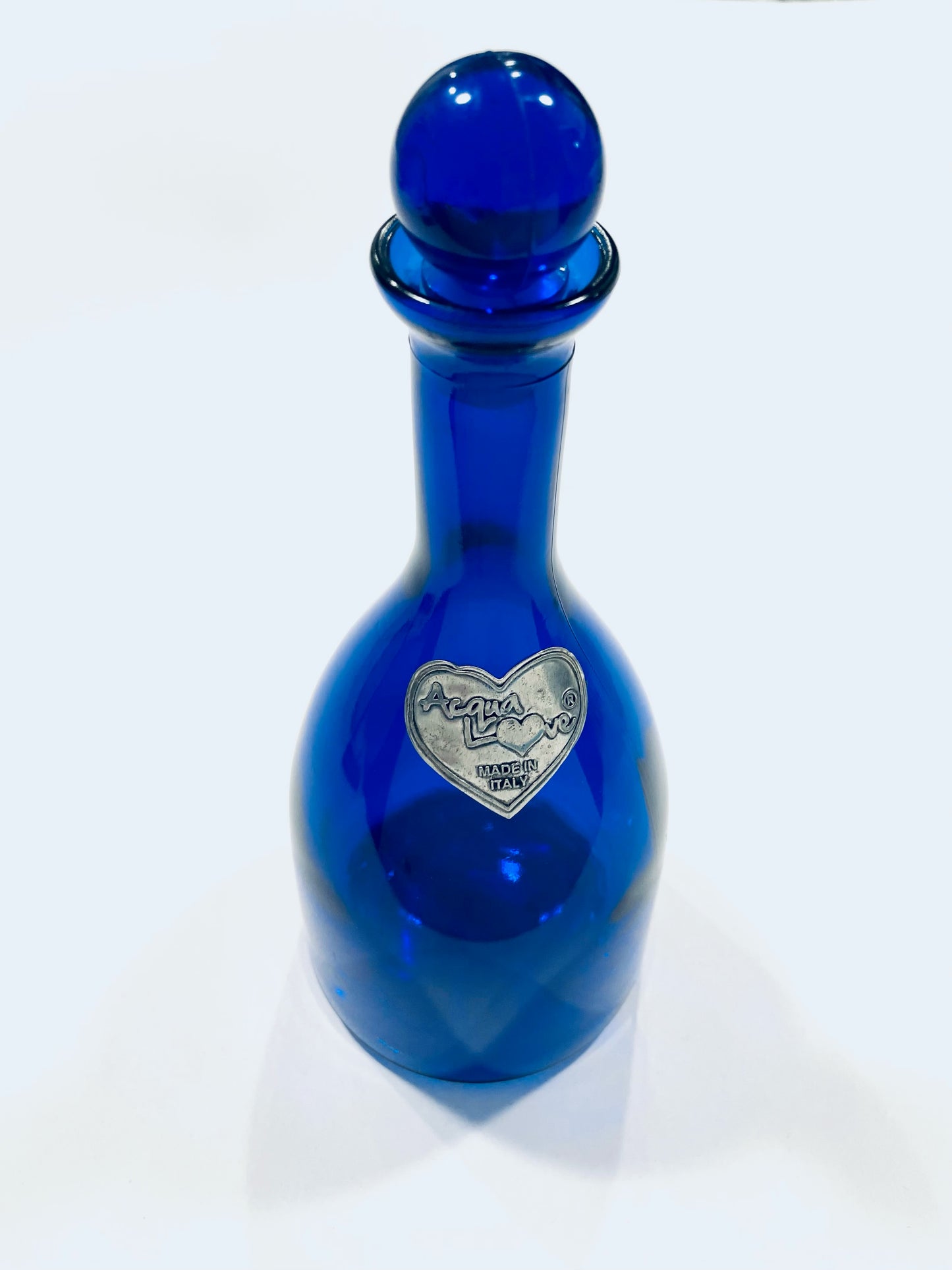 Aqua Love Made In Italy Cobalt Blue glass bottle with a silver heart-shaped label 