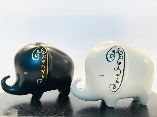 A pair of black and white ceramic elephant-shaped condiment shakers with hand-painted details and gold stamping By Kate Spade 