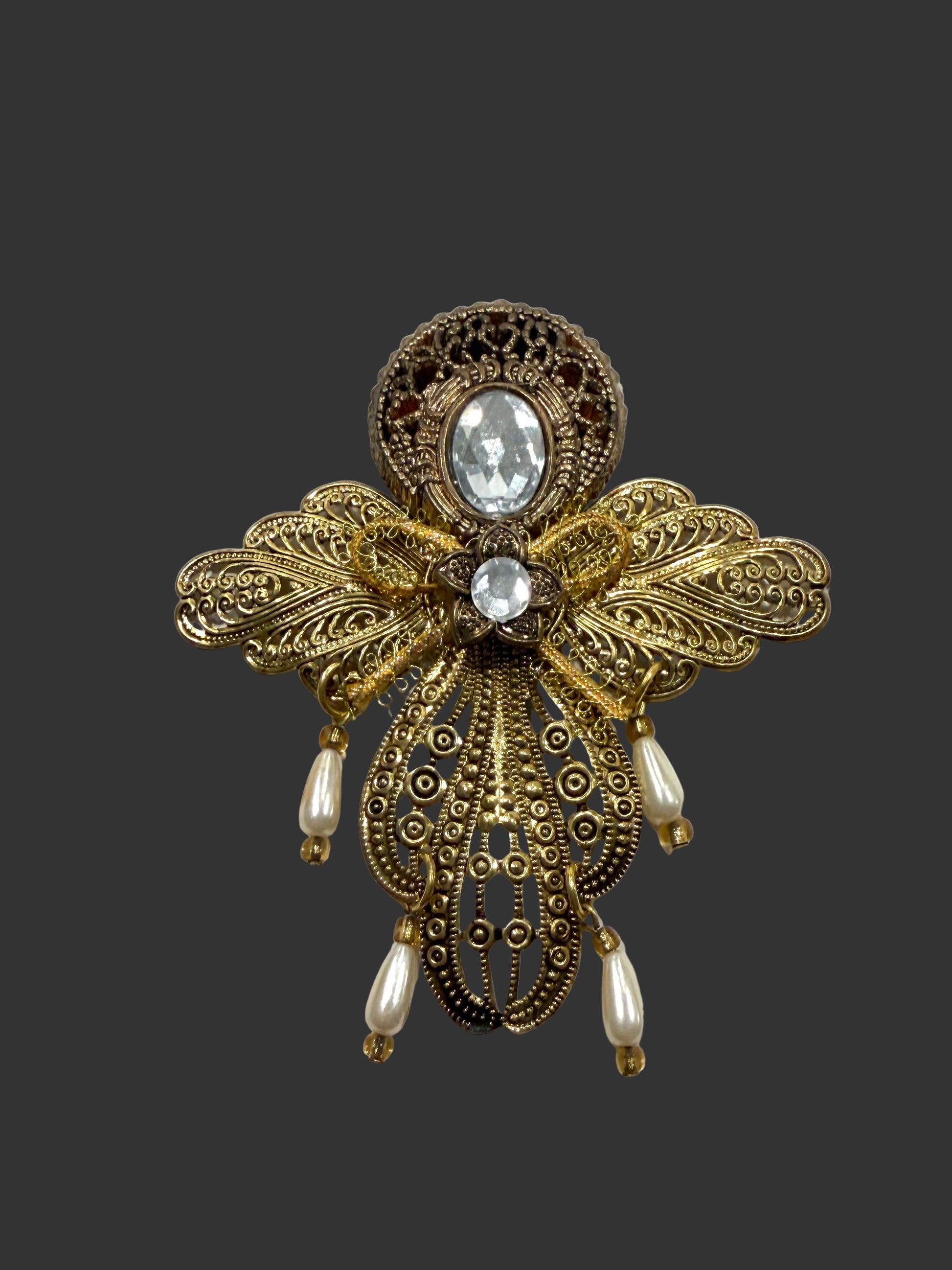 Decorative pendant with intricate gold design, central gemstone, and pearl-like elements 
