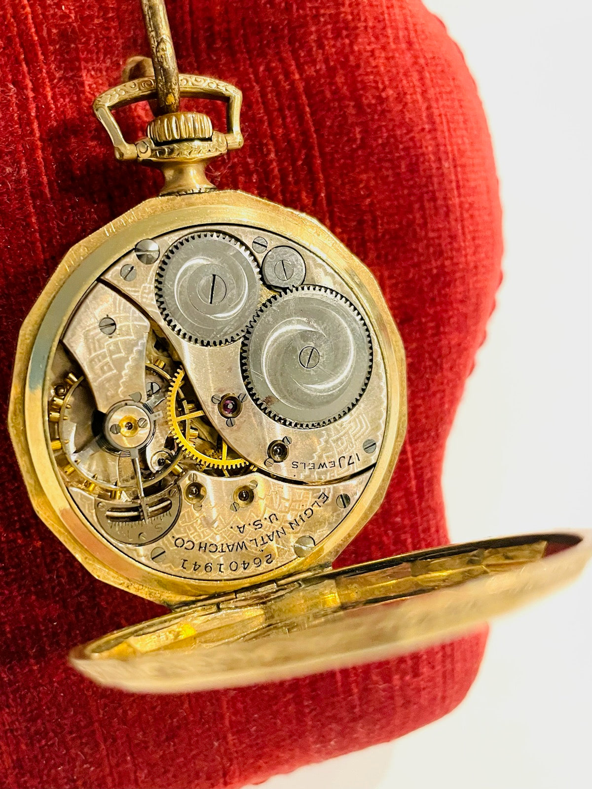 Close-up of a gold Elgin pocket watch with visible mechanical components 