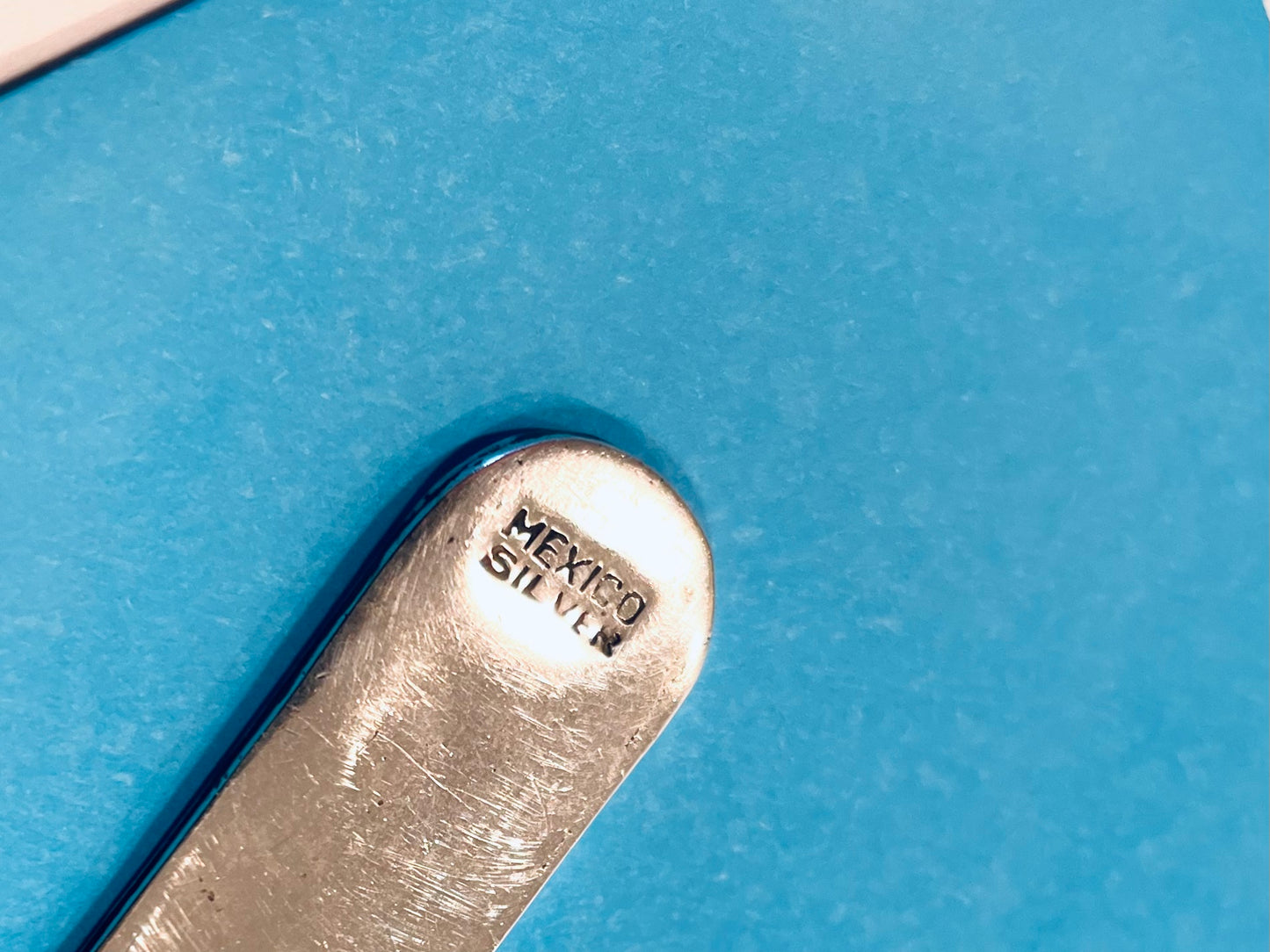 Close-up of a silver object with 'Mexico Silver' stamp on a blue background