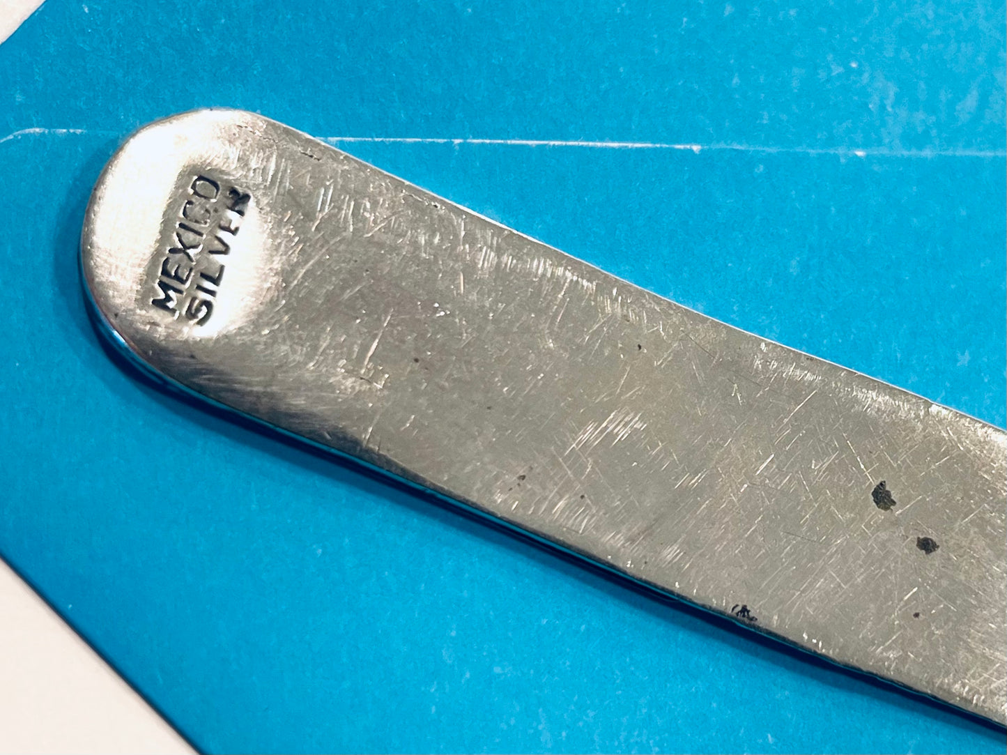 Metallic object with 'Mexico Silver' stamp on a blue background