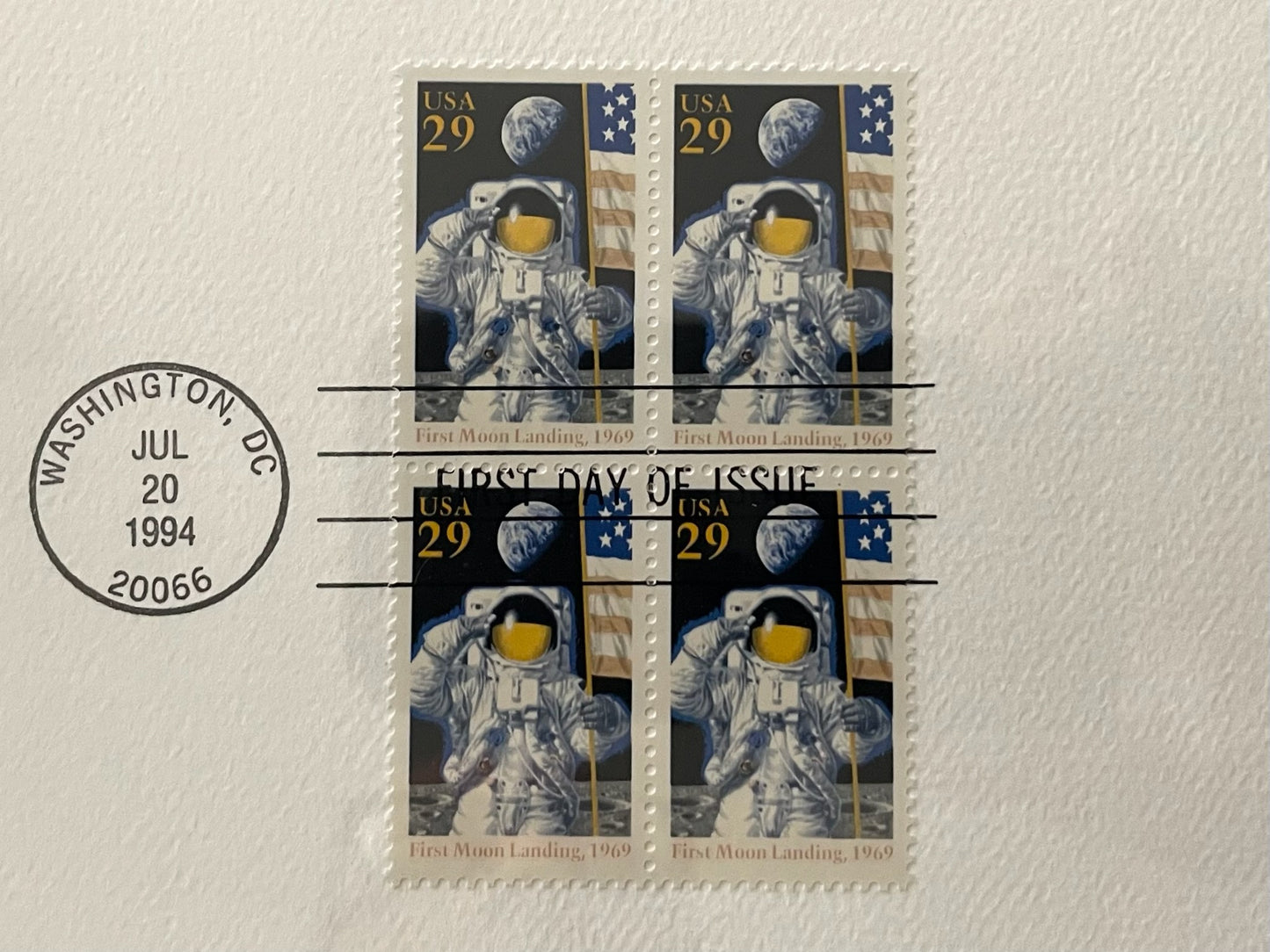 Four stamps featuring astronauts and space-themed designs on a textured surface with a 'First Day of Issue' stamp.