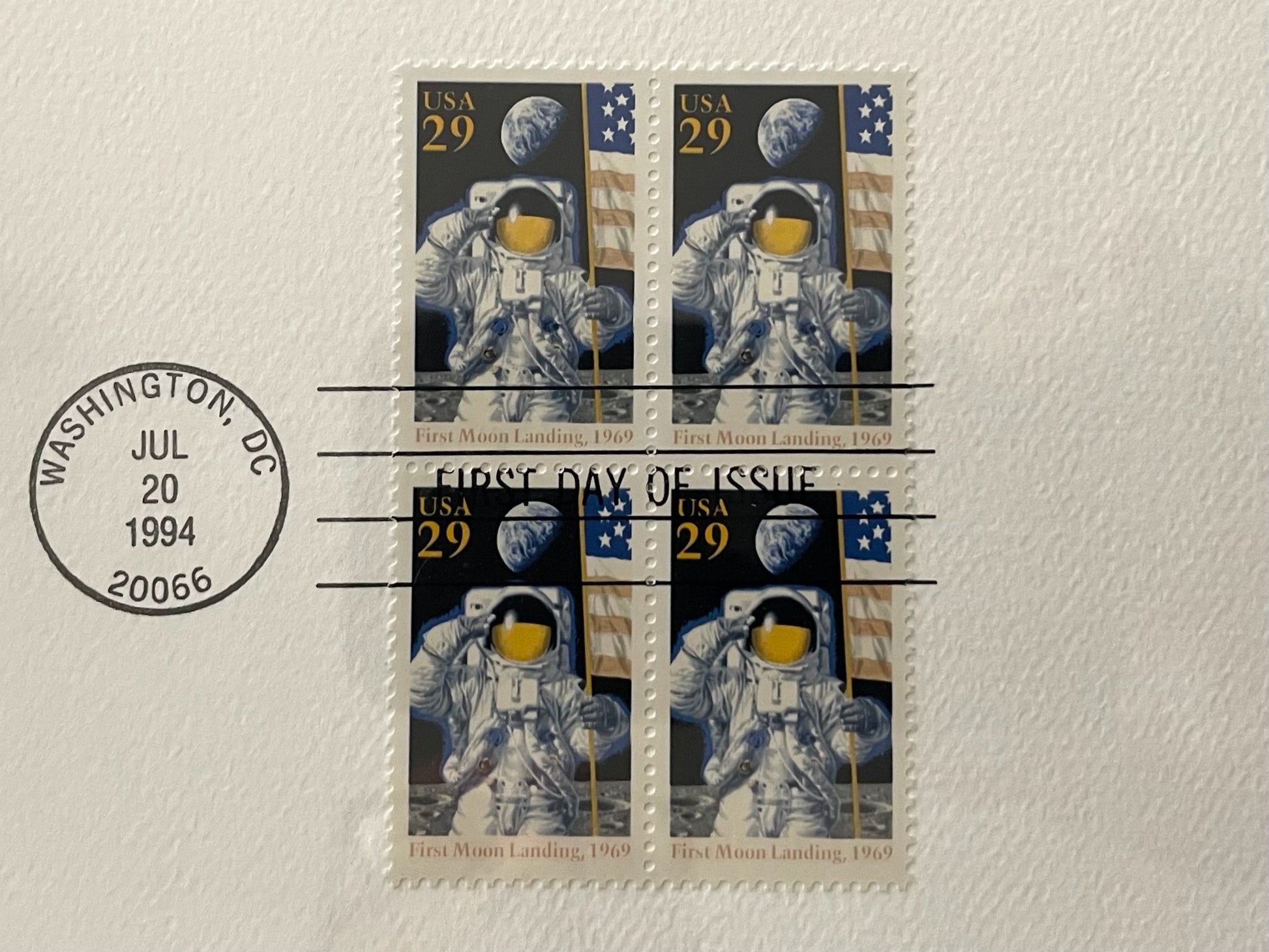 Four stamps featuring astronauts and space-themed designs on a textured surface with a 'First Day of Issue' stamp.