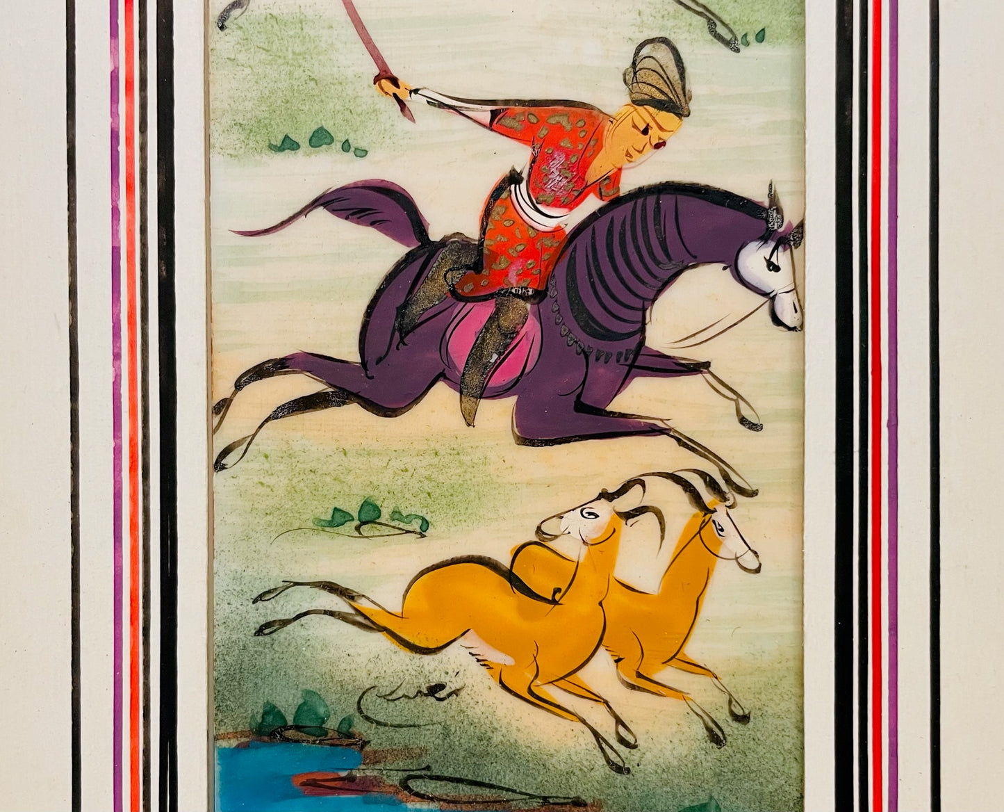 Decorative panel with a horse and rider chasing gazelles, framed with colorful borders.