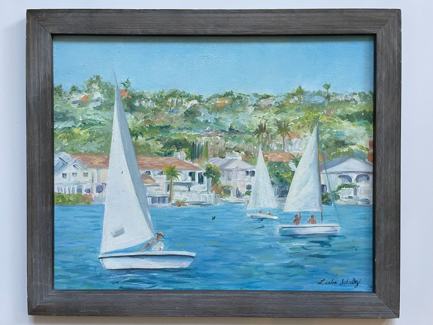 Leslie Schultz Sailing scene with sailboats on a body of water, with houses and trees in the background oil on canvas 