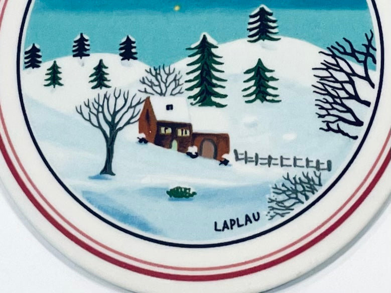 Decorative plate with a winter scene featuring a house, trees, and a lake, with 'Lapland' text.