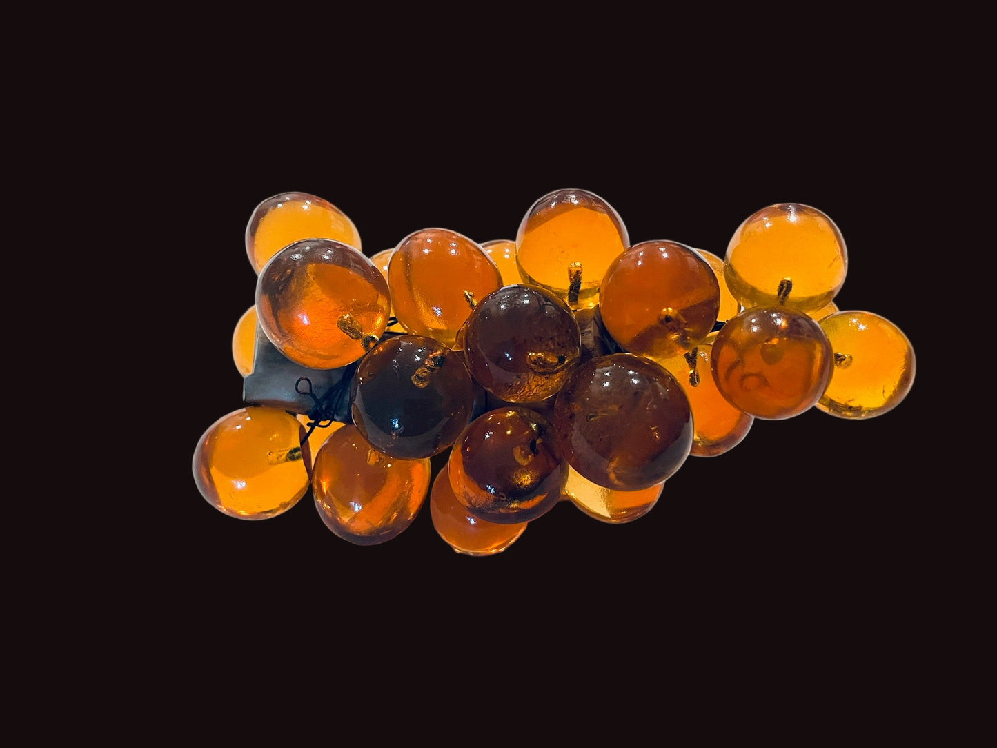 Cluster of translucent orange grapes on a black background